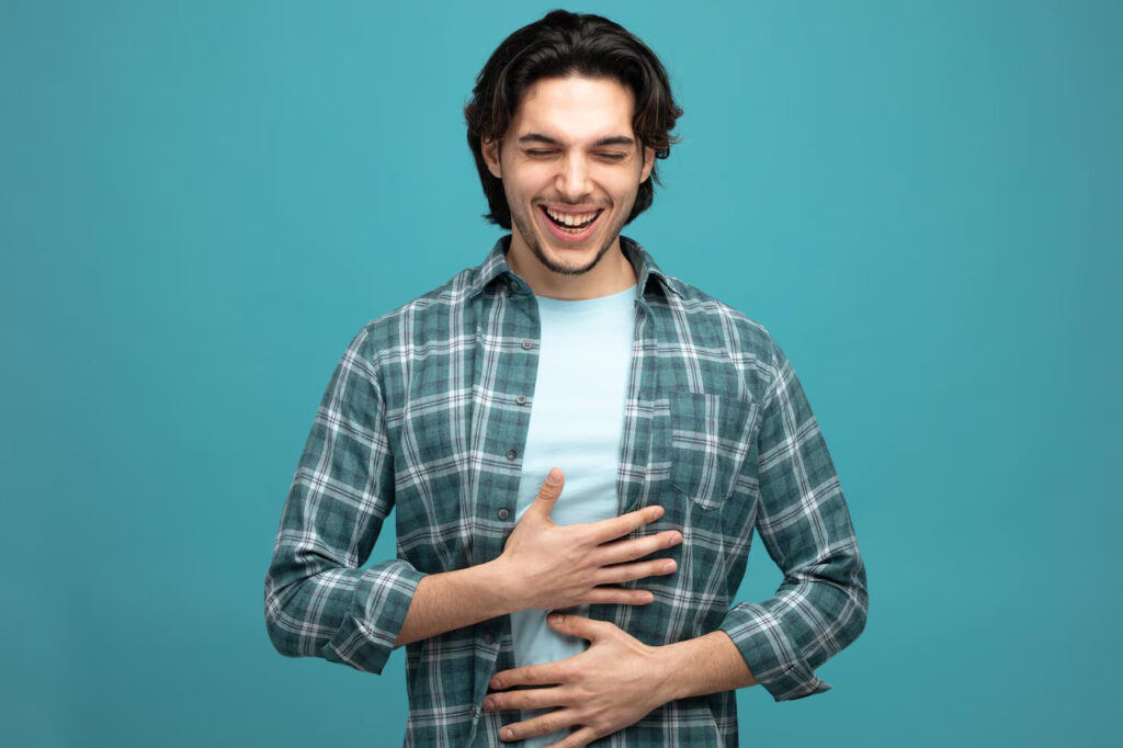 cheerful-young-handsome-man-keeping-hands-belly-laughing-with-closed-eyes-isolated-blue-background