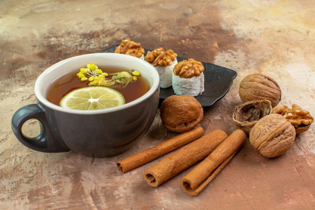 front-view-cup-tea-with-cinnamon-confitures-light-desk