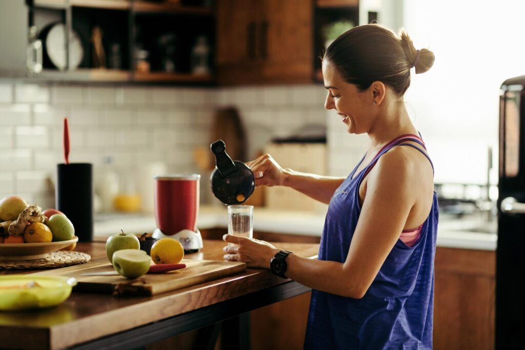 happy-athletic-woman-pouring-fruit-smoothie