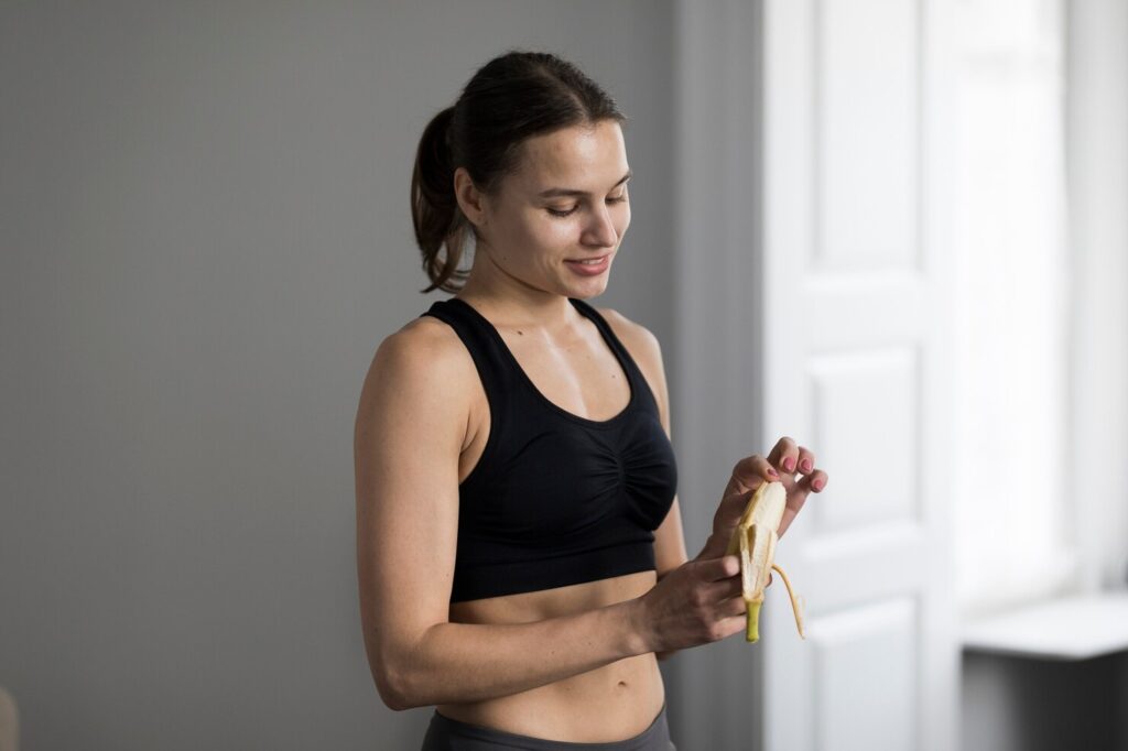 side-view-sporty-woman-peeling-banana